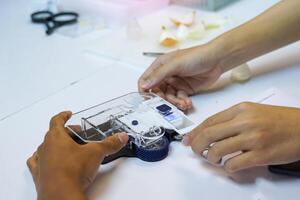 Students conduct science experiments to study plant cells. By placing a slide stained with iodine on a smartphone microscope. Technology that turns a smartphone into a mobile microscope. photo