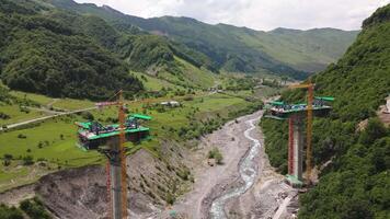 Kazbegi, Georgia - 7th july, 2024 - aerial view cranes and bridge foundation pillars on construction site of new highway road project built by chinese builders.Avalanche bypass tunnel.Tbillisi - Lars video