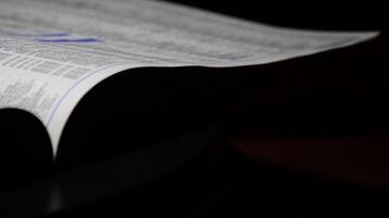 Pages of phone book with names and address rotating in a black background video