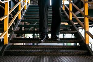 Close-up view of full black wingtip brogue shoes made of genuine leather worn by a male model in a deserted warehouse. Concept photo of classic wingtip brogue shoes in an old building made of iron