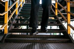 Close-up view of full black wingtip brogue shoes made of genuine leather worn by a male model in a deserted warehouse. Concept photo of classic wingtip brogue shoes in an old building made of iron
