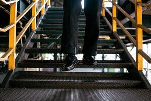 Close-up view of full black wingtip brogue shoes made of genuine leather worn by a male model in a deserted warehouse. Concept photo of classic wingtip brogue shoes in an old building made of iron