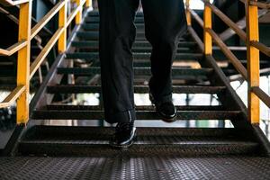 Close-up view of full black wingtip brogue shoes made of genuine leather worn by a male model in a deserted warehouse. Concept photo of classic wingtip brogue shoes in an old building made of iron