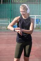 woman exercising in the stadium, checking mobile app on his wristwatch, taking pulse or heart rate after heavy workout outdoor photo