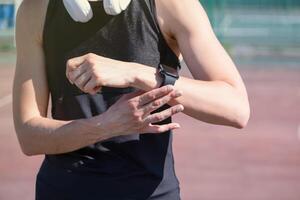 woman exercising in the stadium, checking mobile app on his wristwatch, taking pulse or heart rate after heavy workout outdoor photo