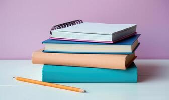 Stack of books on a white desk with a pastel lavender background photo