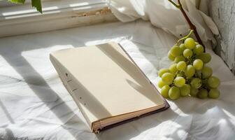 Closed notebook on a white table with a bunch of grapes photo