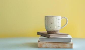 Stack of books on a light gray table with a pastel butter yellow background photo
