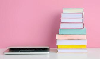 Stack of books on a white desk with a pastel pink background photo