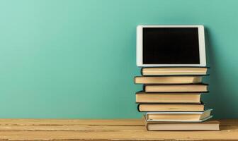 Stack of books on a wooden table with a pastel periwinkle background with a digital tablet photo