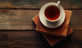 Stack of books with a cup of tea on a white table, window casting shadows photo