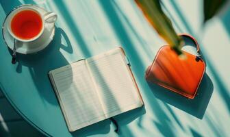 Notebook on a light blue table with a cup of tea, shadow from window photo