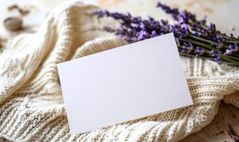 White blank card in a delicate lace frame on a pastel butter yellow table, with a knitted cloth and a small lavender bunch photo