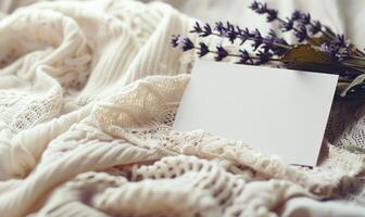 White blank card in a delicate lace frame on a pastel butter yellow table, with a knitted cloth and a small lavender bunch photo