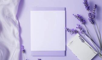 White blank card in a purple frame on a pastel periwinkle table, with a sprig of lavender and a small notebook photo