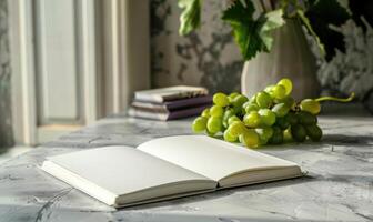 Notebook on a light gray table with a bunch of grapes photo