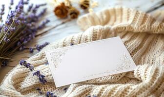 White blank card in a delicate lace frame on a pastel butter yellow table, with a knitted cloth and a small lavender bunch photo