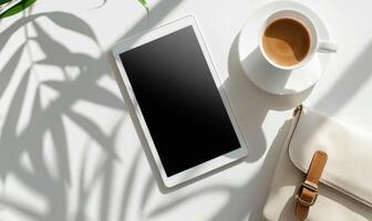 Tablet on a light gray table with a cup of tea on the left, sunlight from window photo