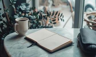 Closed notebook on a light gray table with a cup of coffee on the left and a handbag on the right photo