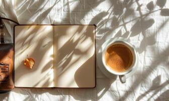 Closed notebook on a white table with a cup of coffee and a handbag photo