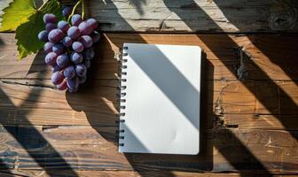 Notebook on a wooden table with a bunch of grapes photo