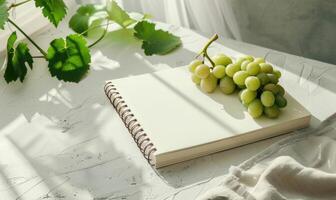 Closed notebook on a light gray table with a bunch of grapes photo