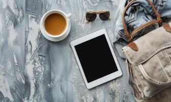 Tablet on a light blue table with a cup of tea on the right, shadow from window, top view photo