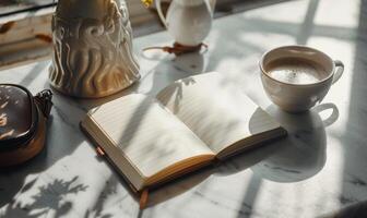 Closed notebook on a light gray table with a cup of coffee on the right and a handbag on the left photo