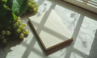 Closed notebook on a light gray table with a bunch of grapes photo