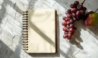Closed notebook on a white table with a bunch of grapes photo
