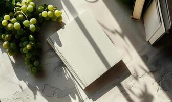 Closed notebook on a light gray table with a bunch of grapes photo