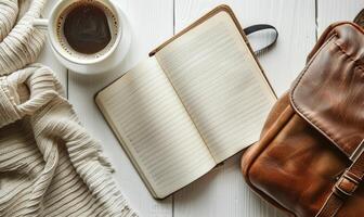 Closed notebook on a white table with a cup of coffee and a handbag photo