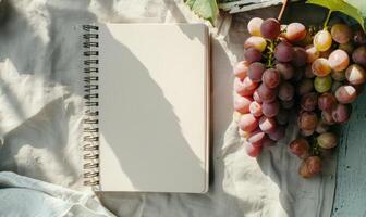 Closed notebook on a light gray table with a bunch of grapes photo