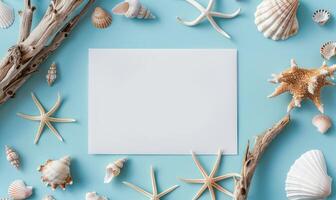 White blank card on a pastel sky blue background, with a small collection of seashells and a piece of driftwood photo