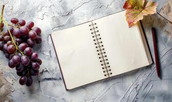 Closed notebook on a light gray table with a bunch of grapes photo