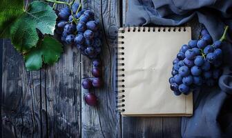 Notebook on a wooden table with a bunch of grapes photo