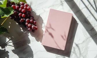 Closed notebook on a white table with a bunch of grapes photo