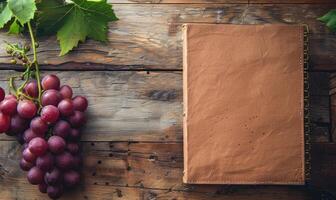 Notebook on a wooden table with a bunch of grapes photo