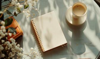 Closed notebook on a light gray table with a cup of coffee on the right and a handbag on the left photo