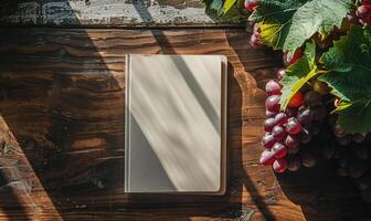 Notebook on a wooden table with a bunch of grapes photo