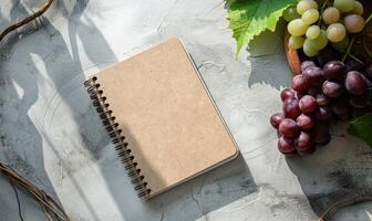 Closed notebook on a light gray table with a bunch of grapes photo
