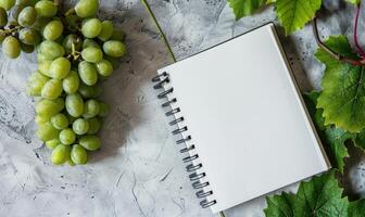 Closed notebook on a light gray table with a bunch of grapes photo