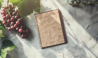 Closed notebook on a light gray table with a bunch of grapes photo