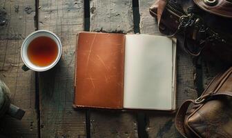 Notebook on a wooden table with a cup of tea and a handbag photo