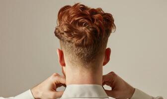 A man with auburn hair on neutral background, back view photo