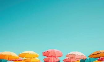 A beach dotted with colorful umbrellas under a clear blue sky, summer tourism background photo