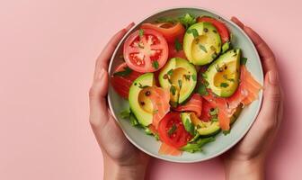 Avocado and smoked salmon salad on a light pink background photo