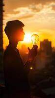a man holding a light bulb in his hand at sunset photo