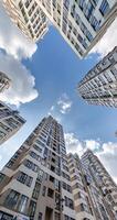 loop circular motion and view up from ground to blue sky among skyscrapers, look at house from bottom up video
