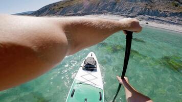 First person view of stand paddle boarding in summer. Men rowing on SUP board on transparent sea. video